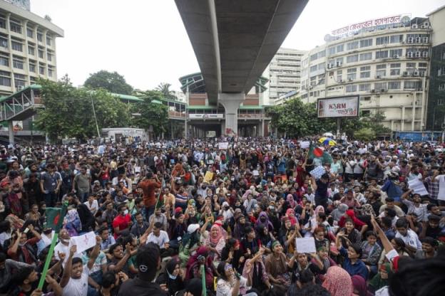 Police clash with protesters under a highway bridge.